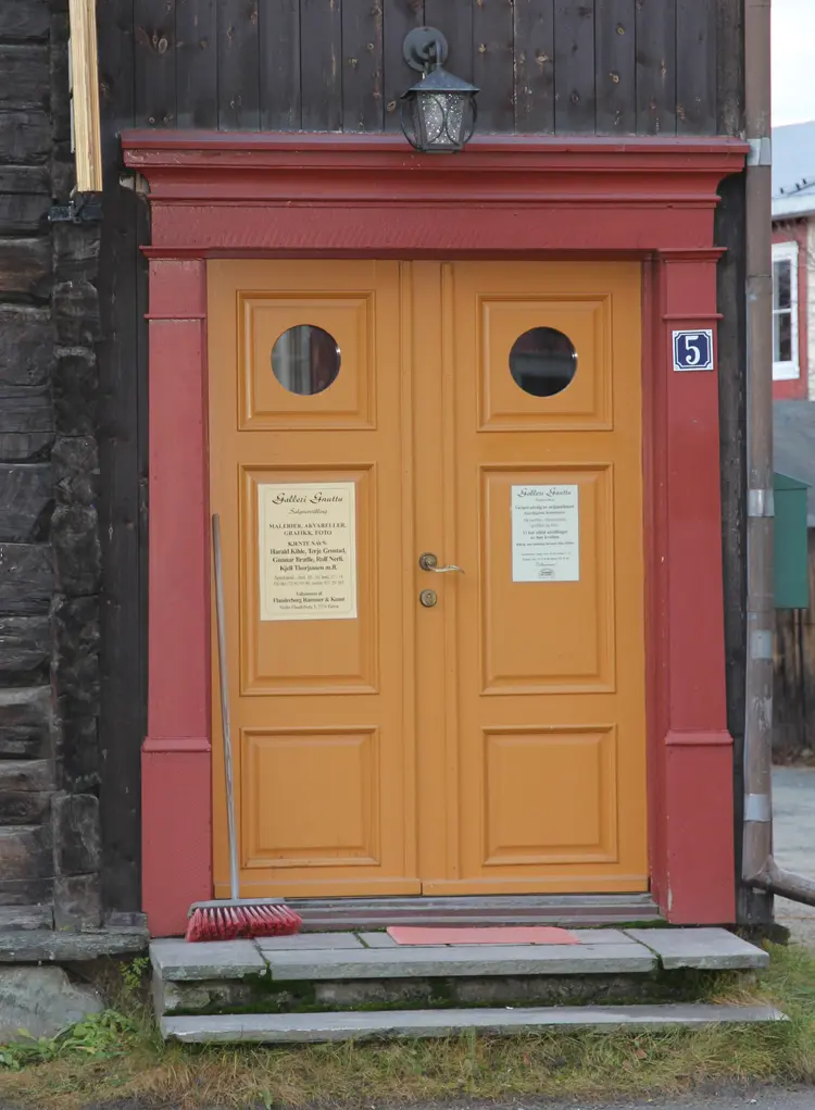 Okergul dør med rød omramming mot umalt tømmer. Røros. Foto: Christel Wigen Grøndahl, Bygg og Bevar