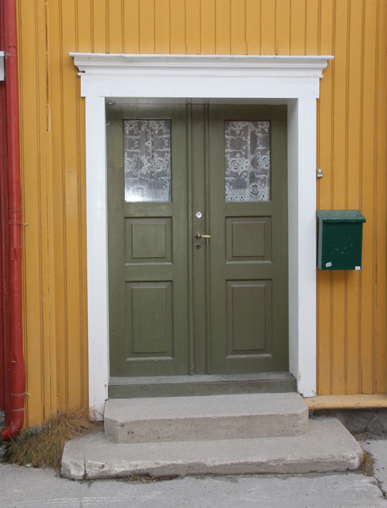 Kromoksidgrønn dør med jernoksidgul kledning, hvit omramming. Røros. Foto: Christel Wigen Grøndahl, Bygg og Bevar