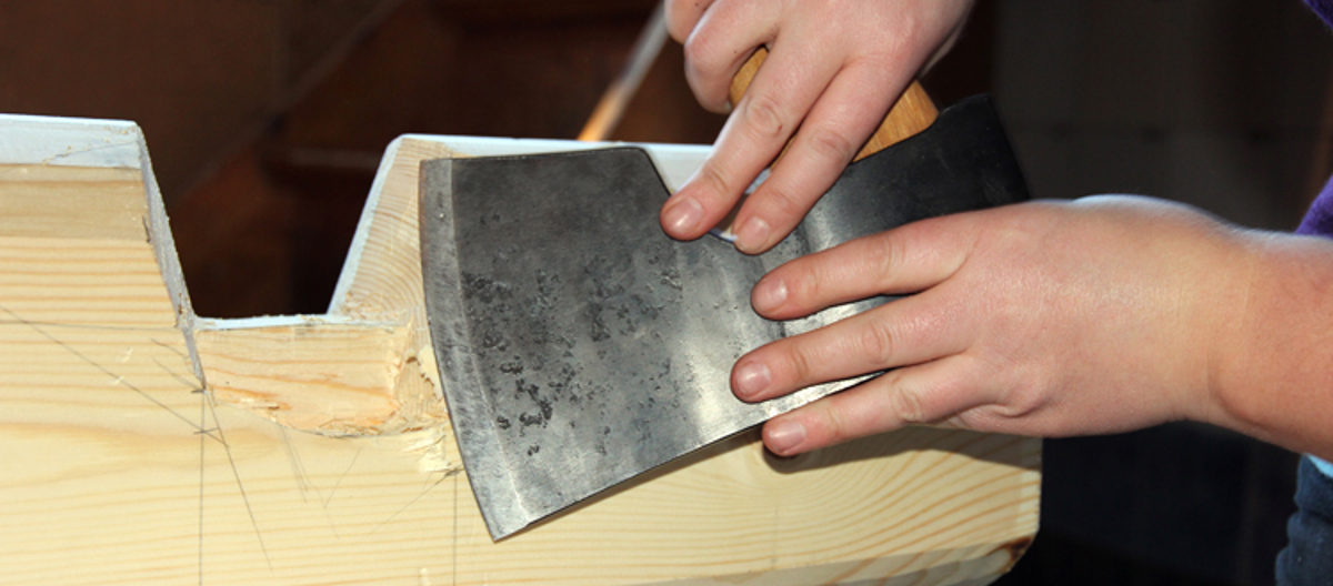 Hege Laugerud finpusser barkelaftet med øksen sin. Foto: Christer Stenby