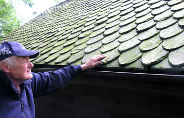 Rognald Stuahaug viser taket på husmannsstua fra Bjoa med original dråpaskifer. Foto: Helge Haugen