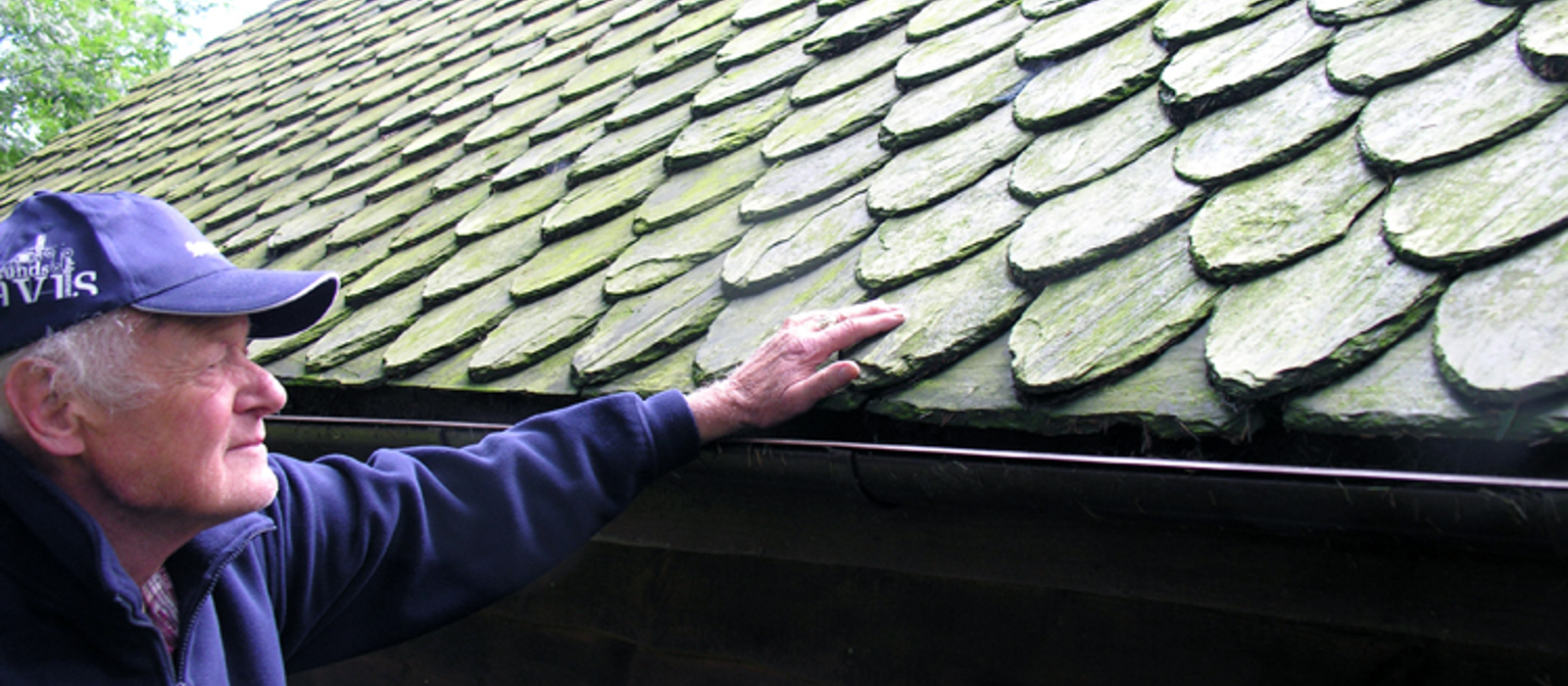 Rognald Stuahaug viser taket på husmannsstua fra Bjoa med original dråpaskifer. Foto: Helge Haugen
