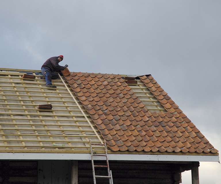 gammel teglstein legges på taket, en lang lekte brukes som siktemål slik at radene blir rette og fine. Foto: Norske Hjem