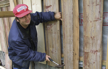 Tor harald Frøyset i ferd med å sette tilbake originalkledningen på svalganshuset fra 1700-tallet som de har flyttet. Foto: Norske Hjem