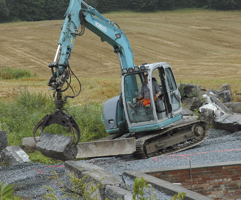 Store grunnmursstein legges på plass med gravemaskin. Foto: Norske Hjem