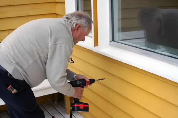 Berg sjekker om det er isolering i ytterveggene. Foto: CEWG