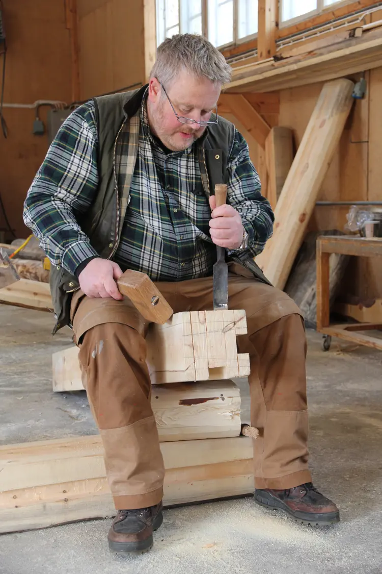 Knut Botnegård: Opprinnelig hovslager og salmaker, interessert i gammelt verktøy og gammel byggeskikk. På kurs for å lære mer om lafting. Knut Botngård arbeider med et bygg som har noen omfar barkelaft og deretter slepplaft, her justeres en stav som skal stå i det laftede hjørnet. Foto: Christer Stenby