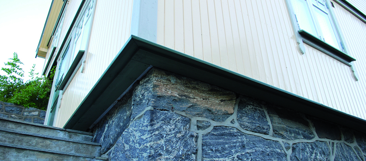 På dette bildet ses et hus hvor ytterveggen er isolert utenfra. Normalt sett ligger panelet tett på grunnmuren. Her har ettersioleringen gjort at veggen stikker svært langt ut. I dette tilfellet er vinduene flyttet tilsvarende - det er svært lite estetisk dersom vinduet blir stående innsunket inne i veggen. Foto: Per-Willy Færgestad