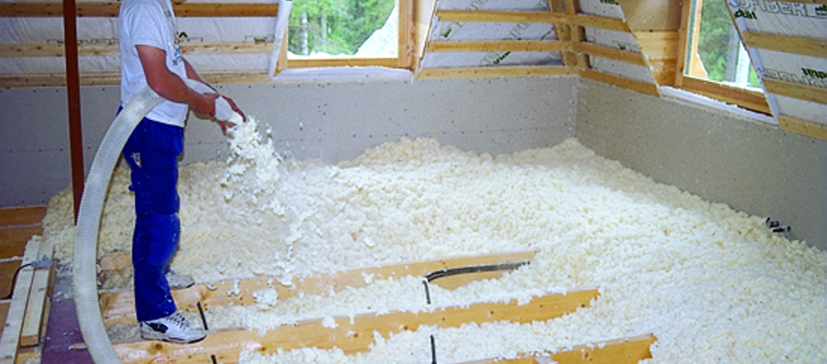 Trefiberisolasjon blåses i bjelkelaget. Foto: Varis Bokalders