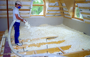Trefiberisolasjon blåses i bjelkelaget. Foto: Varis Bokalders