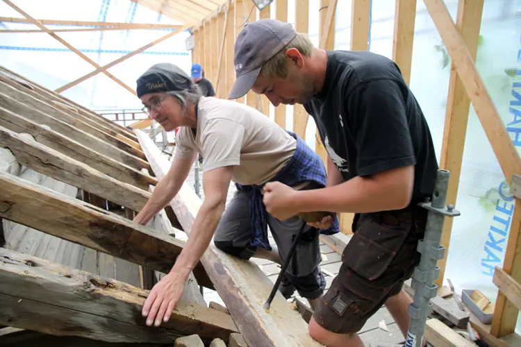 Siv Holmin holder mens Sven Hoftun borer hull til trenaglen med en navar. Foto: Christel Wigen Grøndahl, Bygg og Bevar