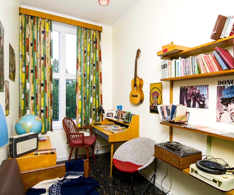 Tenåringsrommet i 1965-leiligheten i Wessels gate 15 har tidstypiske gardiner med geometrisk mønster. Smalt, tidstypisk gardinbrett i palisander. Foto: Norsk Folkemuseum